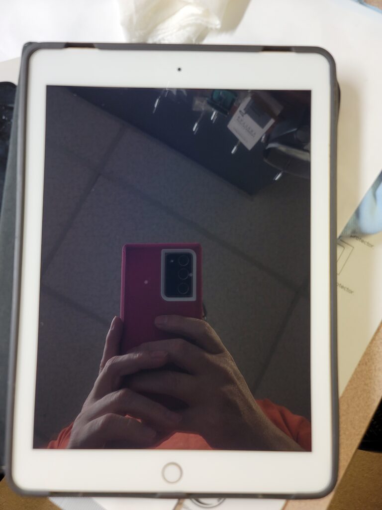 Reflection of person holding pink smartphone on tablet