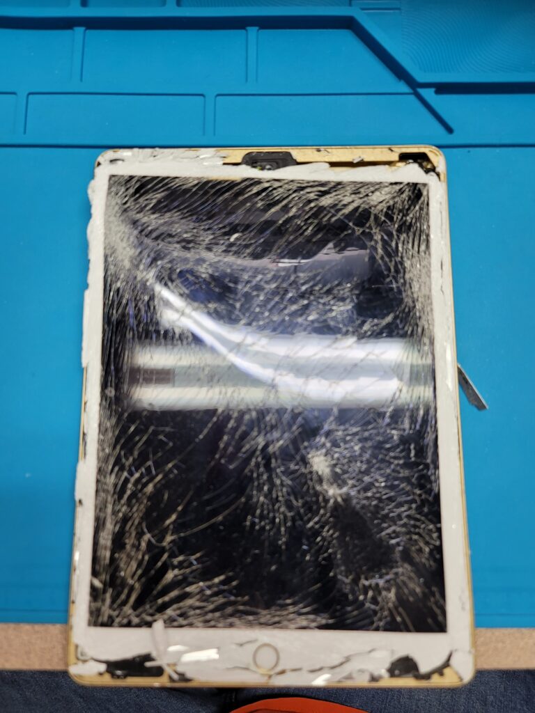 Severely cracked tablet screen on repair mat