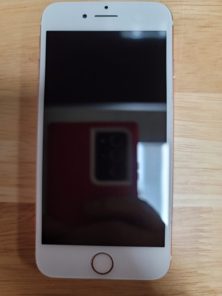 White smartphone with black screen on wooden table