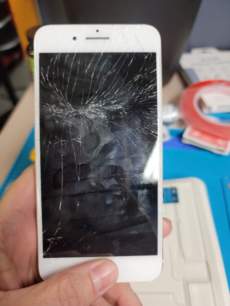 Hand holding smartphone with shattered screen